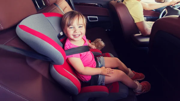 Счастливый ребенок сидит в автокресле и отец вождения — стоковое фото