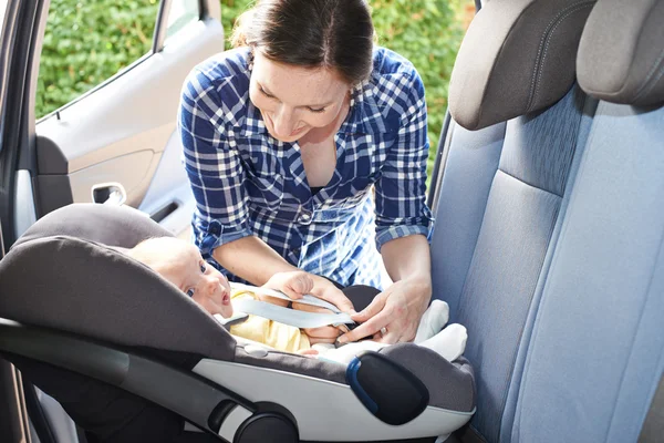 Мать положить ребенка в сиденье автомобиля для путешествие — стоковое фото